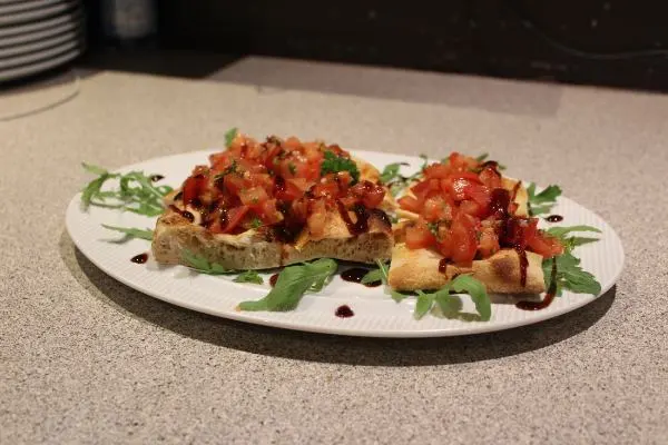 Ein Teller mit zwei köstlichen Bruschetta-Sandwiches, die mit frischen Zutaten belegt sind.